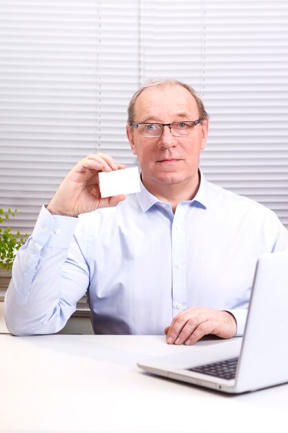 A man in the office at the computer holds a sign in his hands.