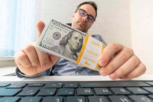 A man in the office counts the money he earned businessman\
holding dollars bribery and corruption concept profit from online\
business joyful worker holds money in his hand