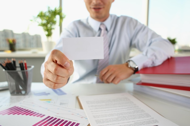 A man in the office holds out a business card closeup