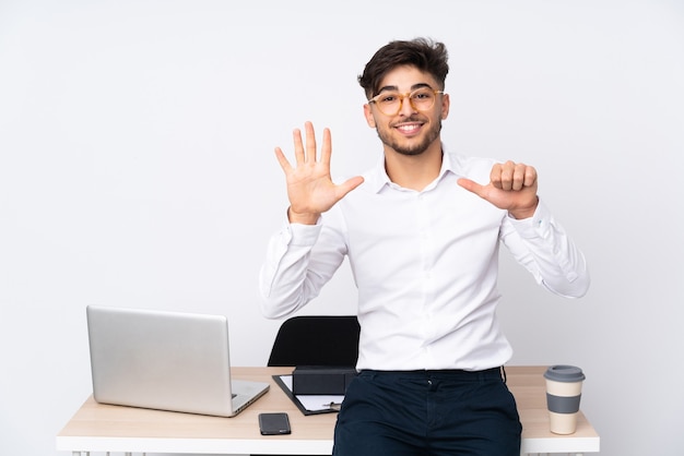 Uomo in un ufficio isolato su bianco contando sei con le dita