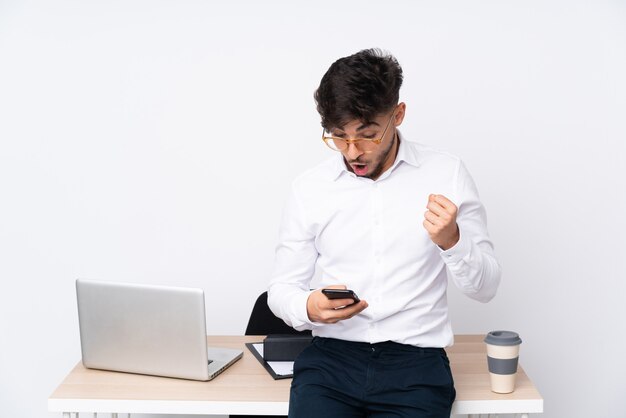 Man in a office isolated on white wall surprised and sending a message