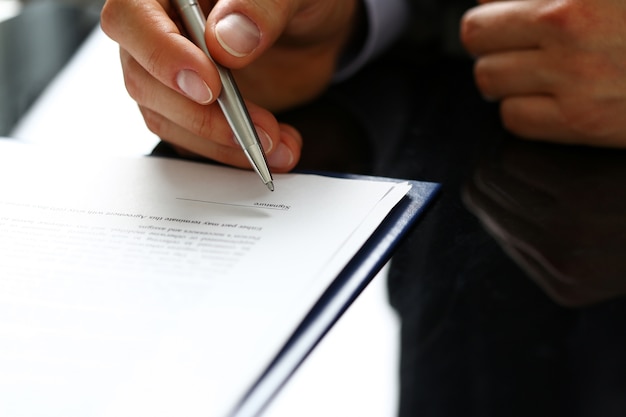 Man in office reading and signing contract