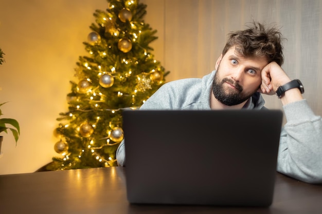 A man in the office tired from work and shaggy sits in front of a laptop and works