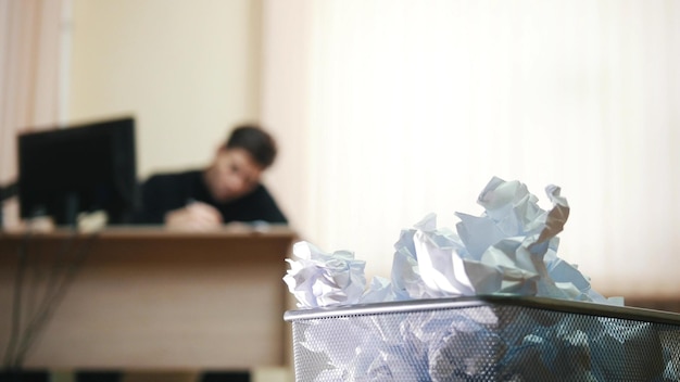 A man in office writing something focus on the trashcan