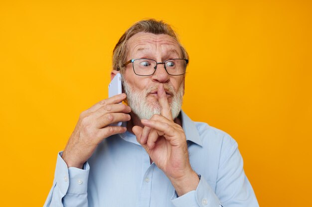 Man old man with phone posing on yellow background