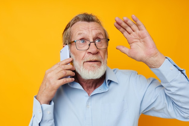 Man old man with phone posing on yellow background