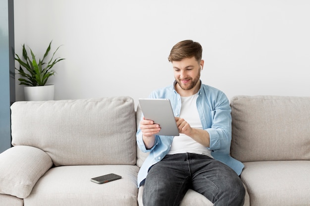 写真 タブレットを使用してソファの上の男