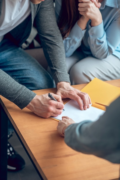 Man ondertekening document voor vrouw en makelaar