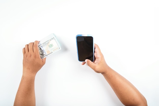 A man in one hand is using a smartphone and the other hand is holding a dollar bill