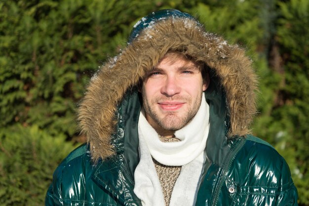 Man ongeschoren draag warme jas met bont besneeuwde natuur achtergrond. hipster wintermode. voorbereid op weersveranderingen. winter stijlvolle herenkleding. winterkostuum. guy wear winterjas met harige capuchon.