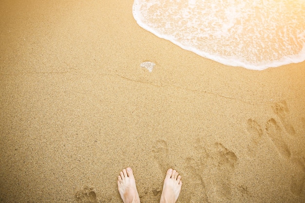 Man ontspant blootsvoets op het strand Guy's benen op het zand Golven aan de oceaanzijde Zomervakantie Reisconcept