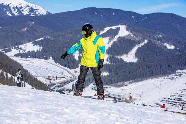 Man op de top van de heuvel met snowboard in zonnige dag. winter bergen