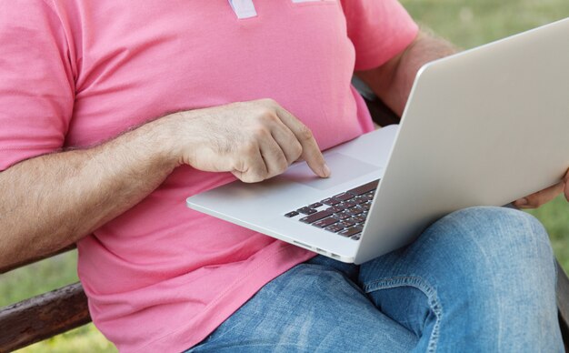 Man op een bankje met behulp van een laptop