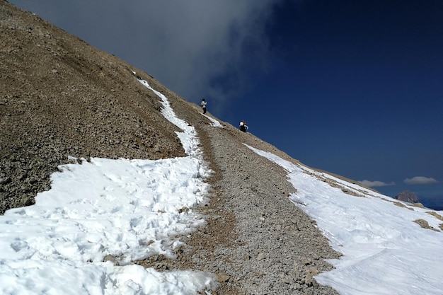 Man op een besneeuwde berg tegen de lucht