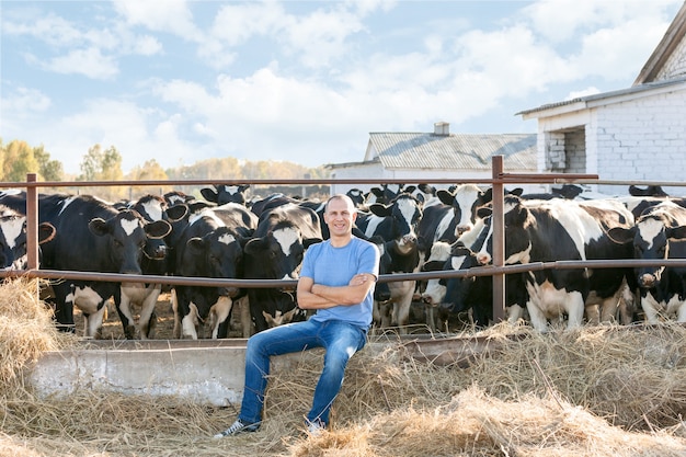 Man op een boerderij omringd door koeien