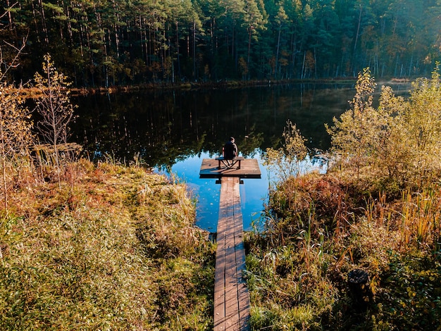 Foto man op een houten promenade bij een meer bij zonsopgang