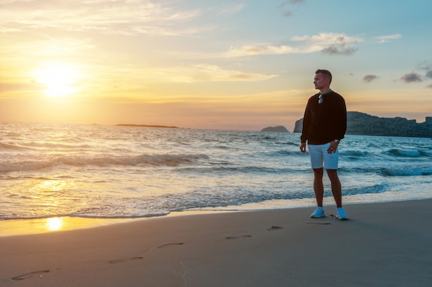 Man op een tropisch strand tijdens zonsondergang