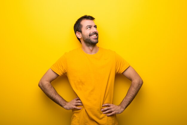 Man op geïsoleerde levendige gele kleur poseren met armen op heup en lachen