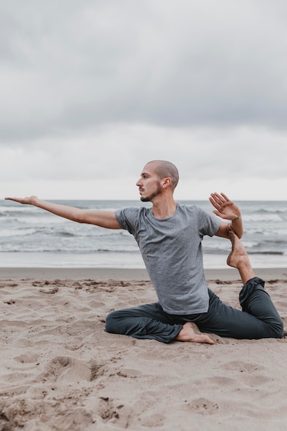 Foto man op het strand beoefenen van yoga-oefeningen