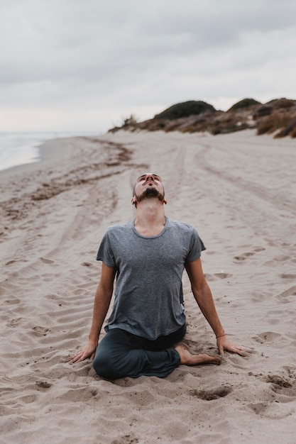 Man op het strand beoefenen van yoga-ontspanning