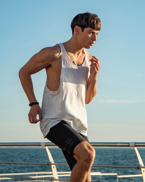 Foto man op het strand uit te werken in tanktop