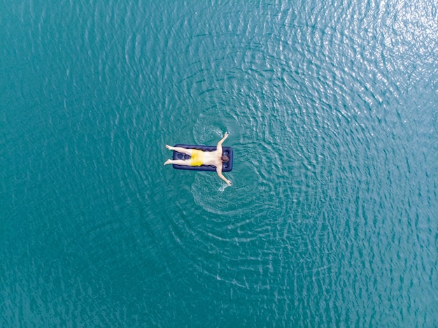 Man op matras in blauw water zomertijd concept