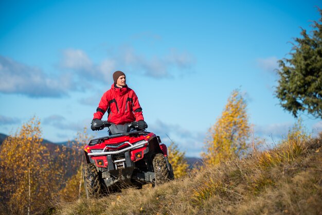 man op rode ATV quad bike tegen blauwe hemel