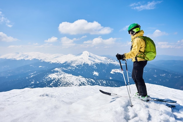 Man op ski op de top geniet van een spectaculair uitzicht op het berglandschap onder de blauwe hemel