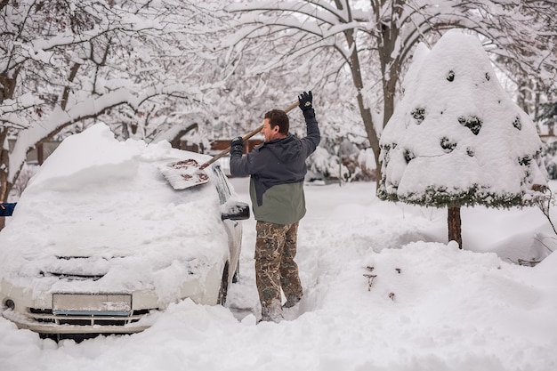 Man op straat op een winterse dag maakt de auto sneeuwvrij