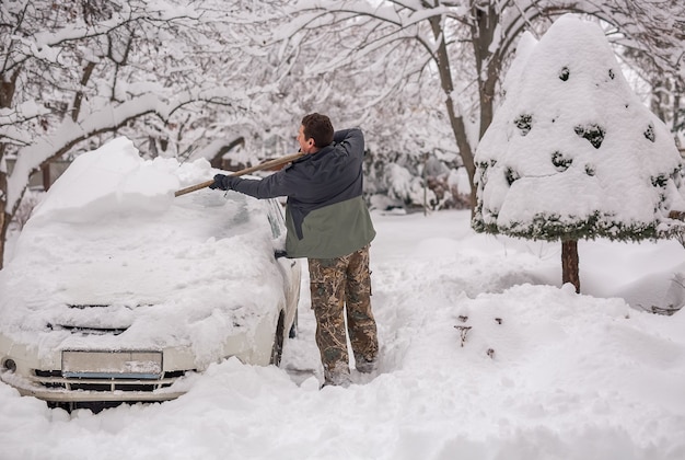 Man op straat op een winterse dag maakt de auto sneeuwvrij