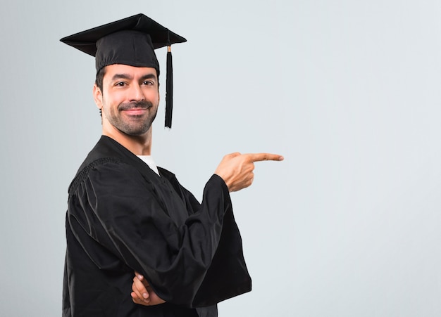 Man op zijn afstuderen dag Universele wijzende vinger naar de kant en de presentatie van een product