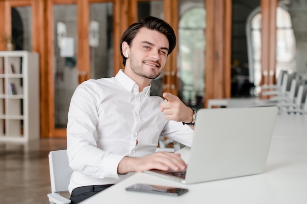 Man op zijn werkplek met telefoon en laptop op kantoor