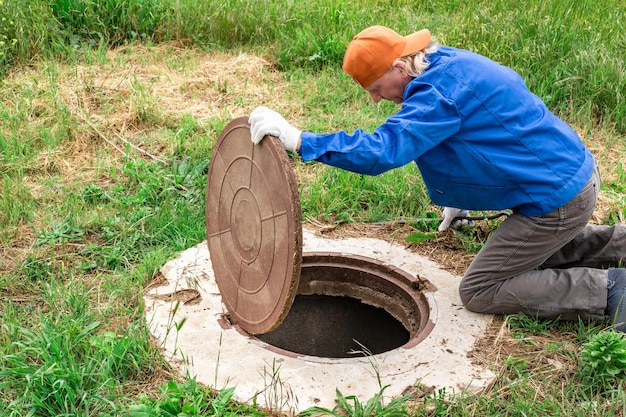 Photo the man opened the cover of the sewer manhole to pump out the sewage