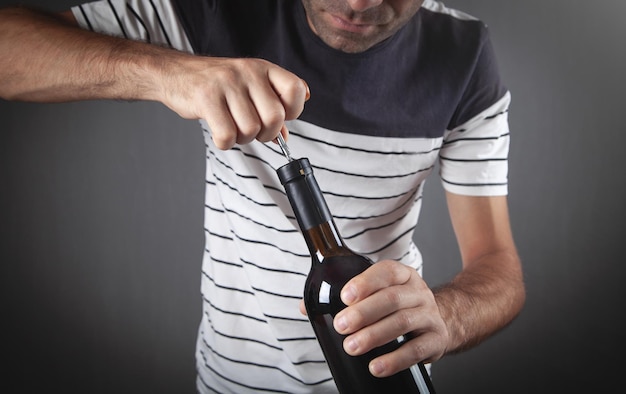 Foto uomo che apre una bottiglia di vino con il cavatappi