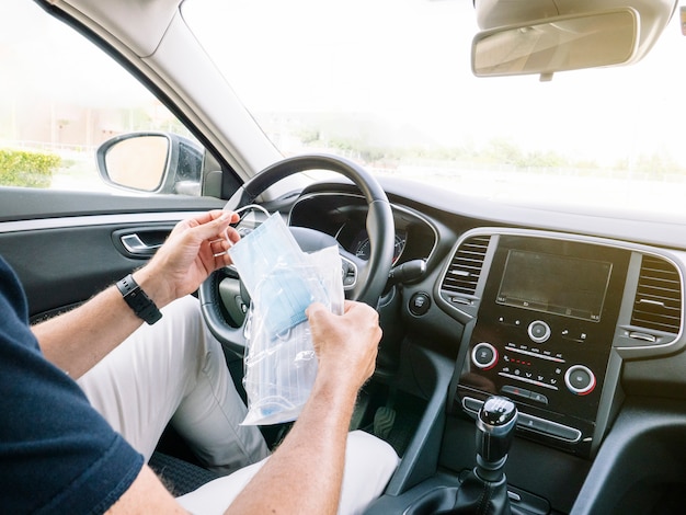 車の中でフェイスマスクと封筒を開く男