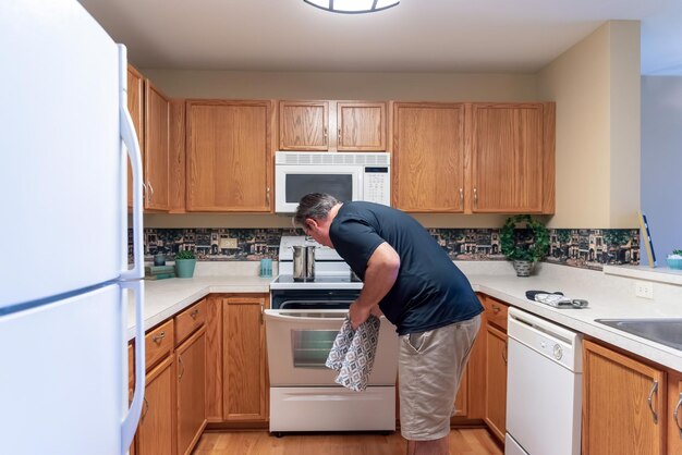 Photo man opening oven in kitchen at home