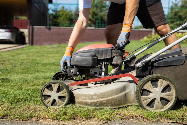 Man opens the fuel tank cap of lawn mower to refuel