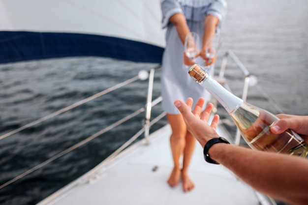 Foto man opent een fles champagne in het luxejacht.