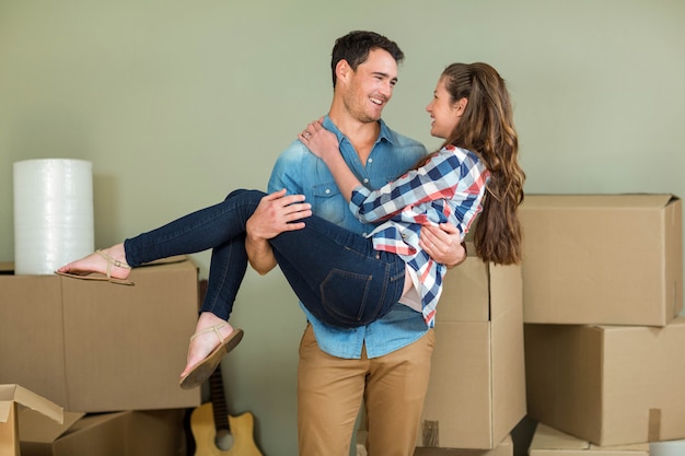 Man opheffing vrouw in zijn armen in hun nieuwe huis