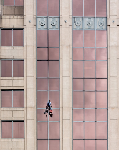 Foto man opknoping van een veiligheid touw schoonmaken gebouw ramen