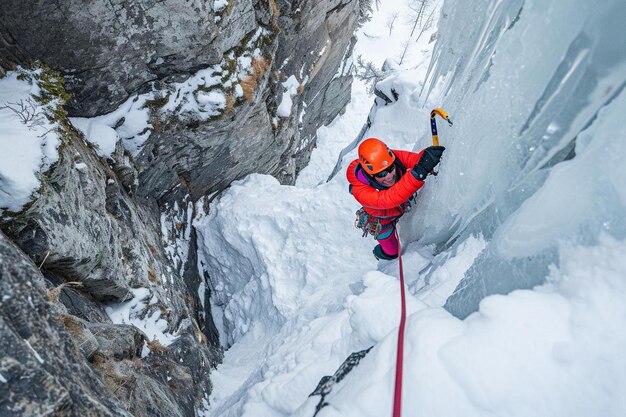 Foto un uomo con una giacca arancione che si arrampica su una montagna