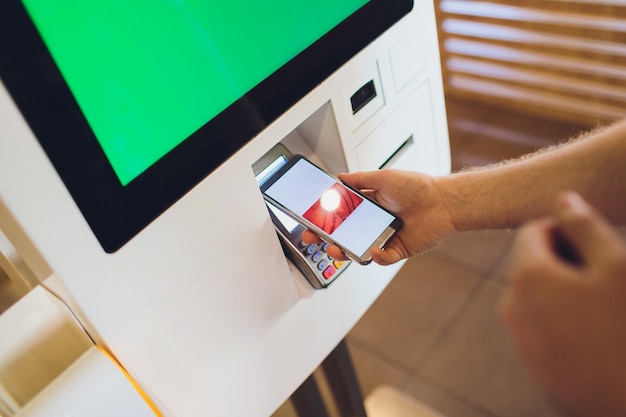 A man orders food in the touch screen terminal with electronic menu in fast food restaurant