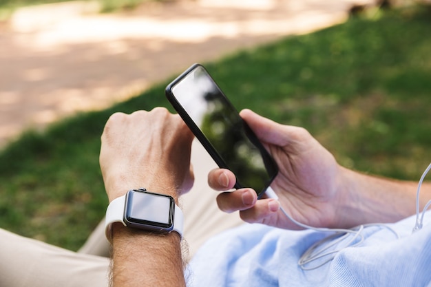 Man outdoors using mobile phone and watch outdoors.