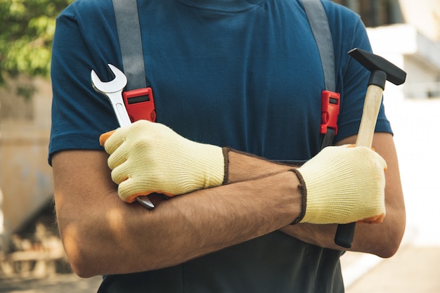 Foto l'uomo in tuta tiene gli strumenti di costruzione all'aperto