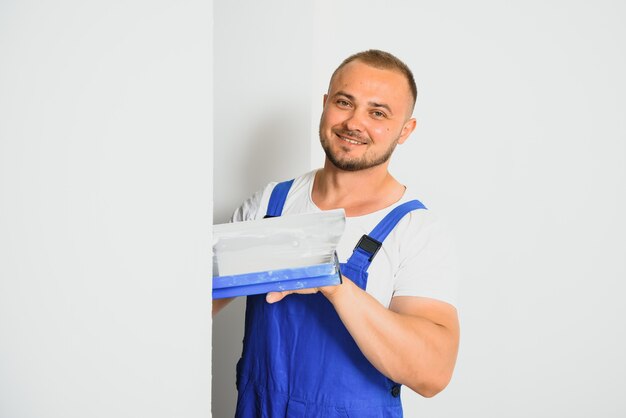 A man in overalls uses a trowel to cover the wall with cement