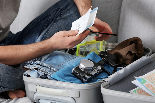 Man packing his grey suitcase in living room