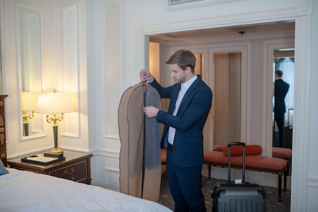 A man packing his official costume for a business trip