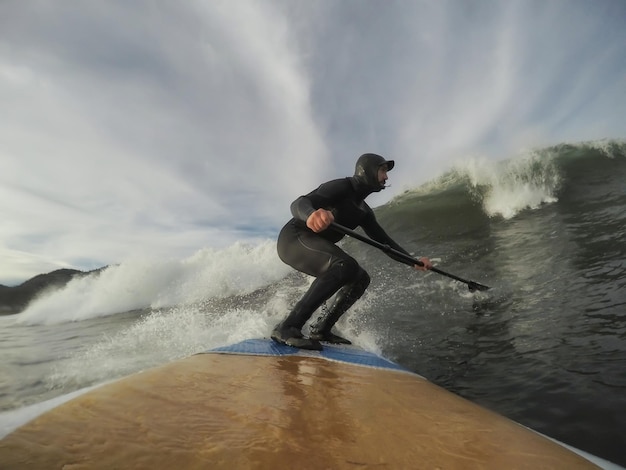 Man Paddle Boarding and Riding Waves