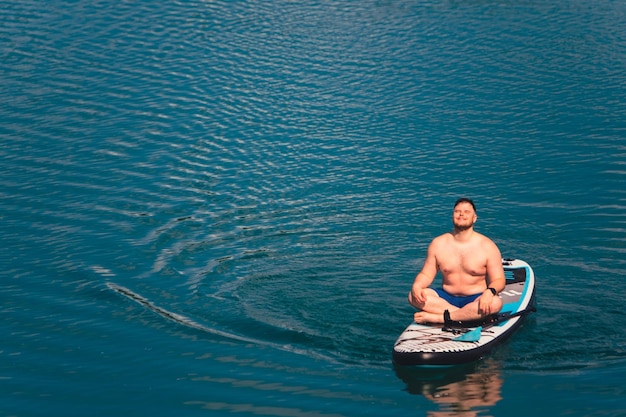 湖の真ん中でパドルボードに乗る男性