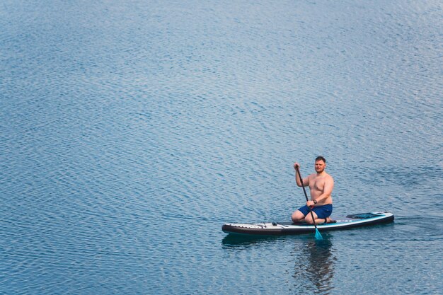 Foto uomo su paddleboard in mezzo al lago